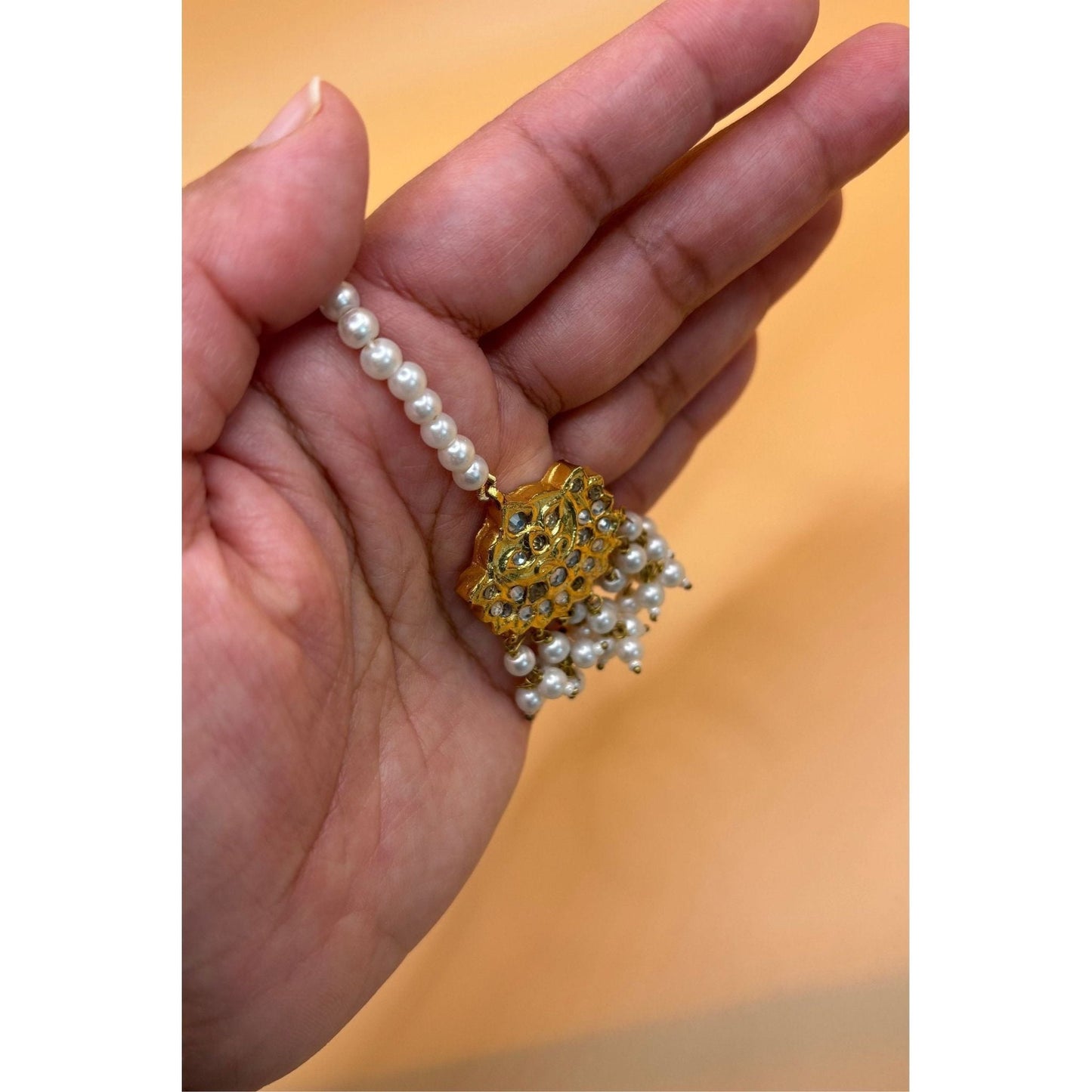 This small vintage tikka with pearls complements all face shapes and evokes a classic aesthetic. The perfect accessory for any occasion, it effortlessly adds an elegant touch to any outfit. Its timeless design is sure to make a statement.