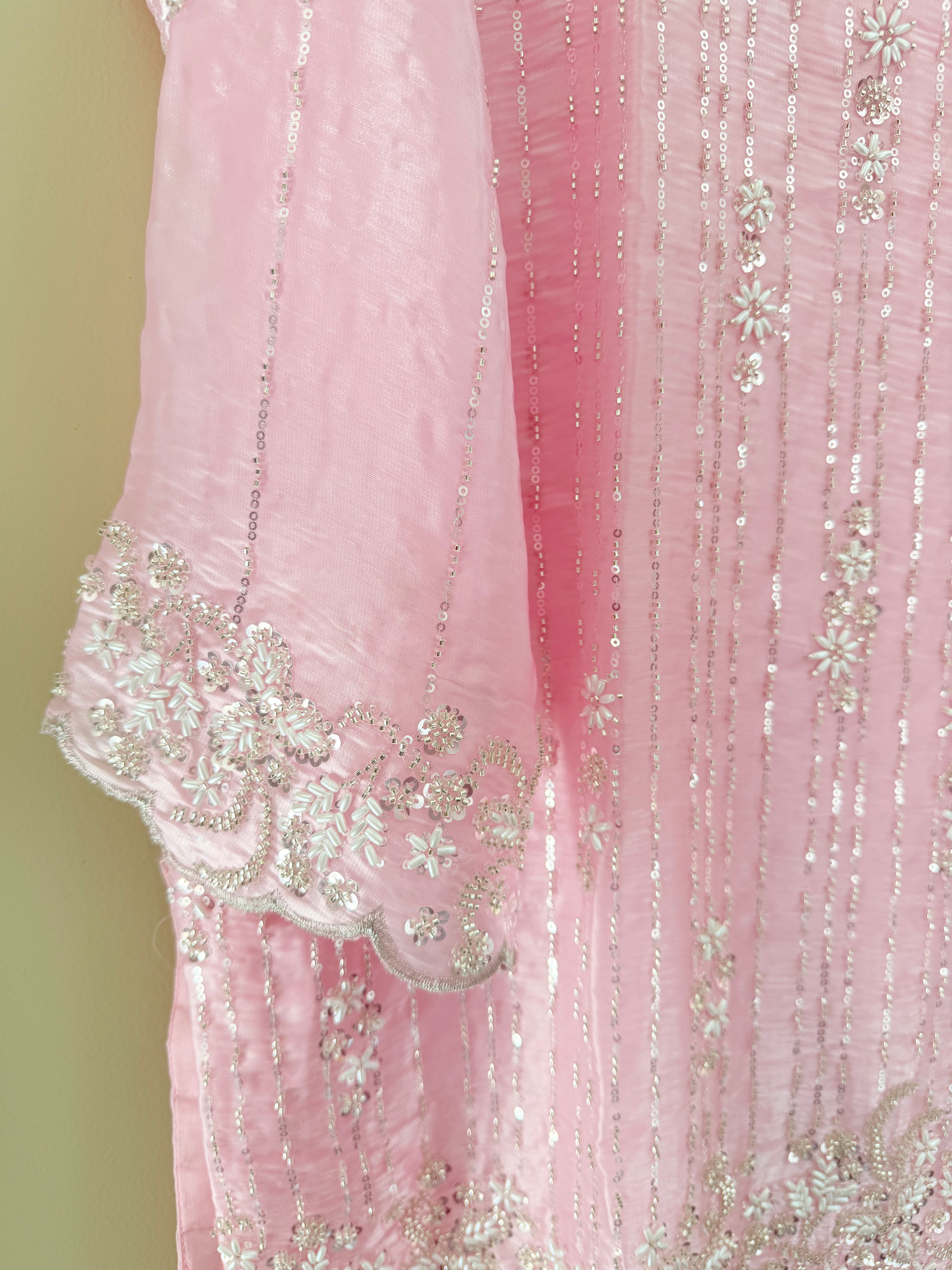 Close-up of a pink fabric with floral embroidery on a light green background