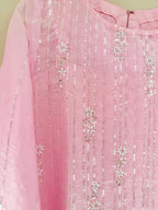 Close-up of a pink fabric with silver sequin and floral patterns on a light green background