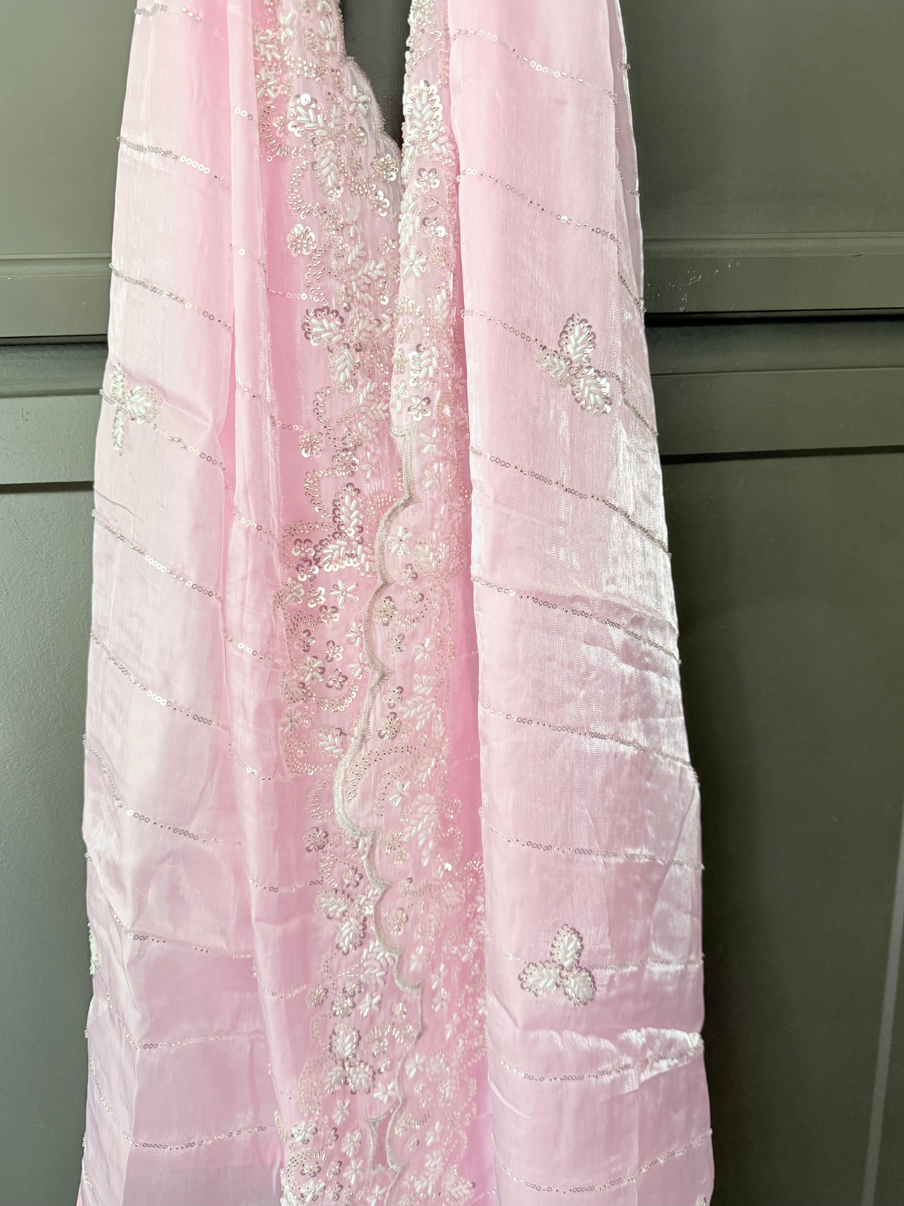 Pink embroidered fabric against a neutral background