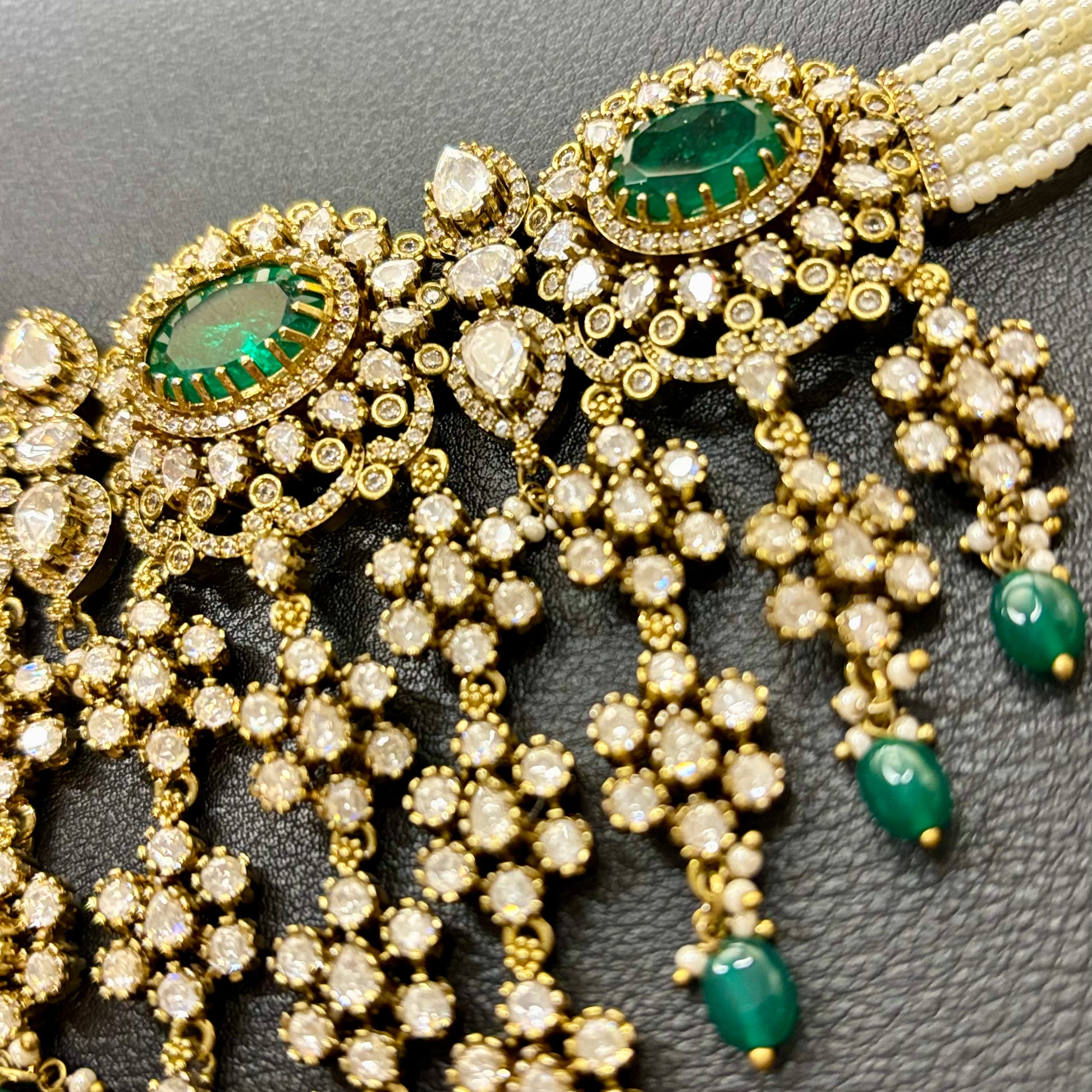 Ornate gold and green gemstone jewelry on a dark background