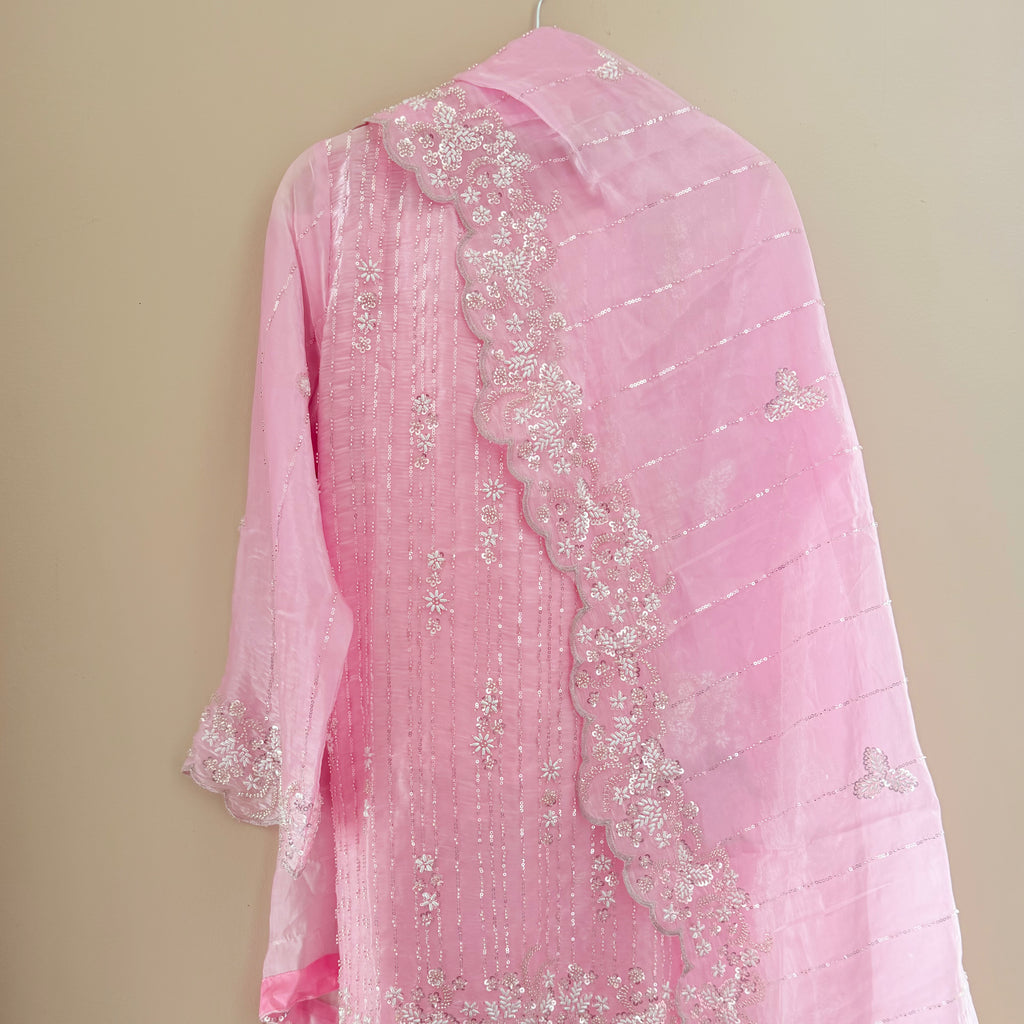 Pink embroidered garment on a beige background