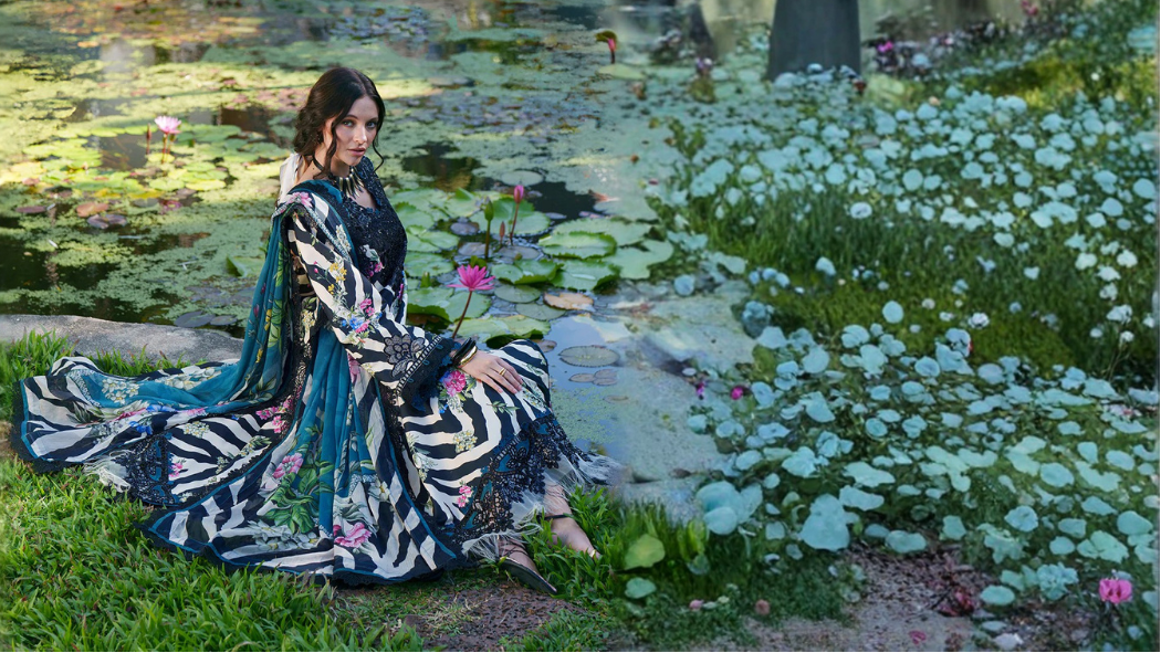 Woman in a floral dress sitting by a pond with lily pads in a park setting