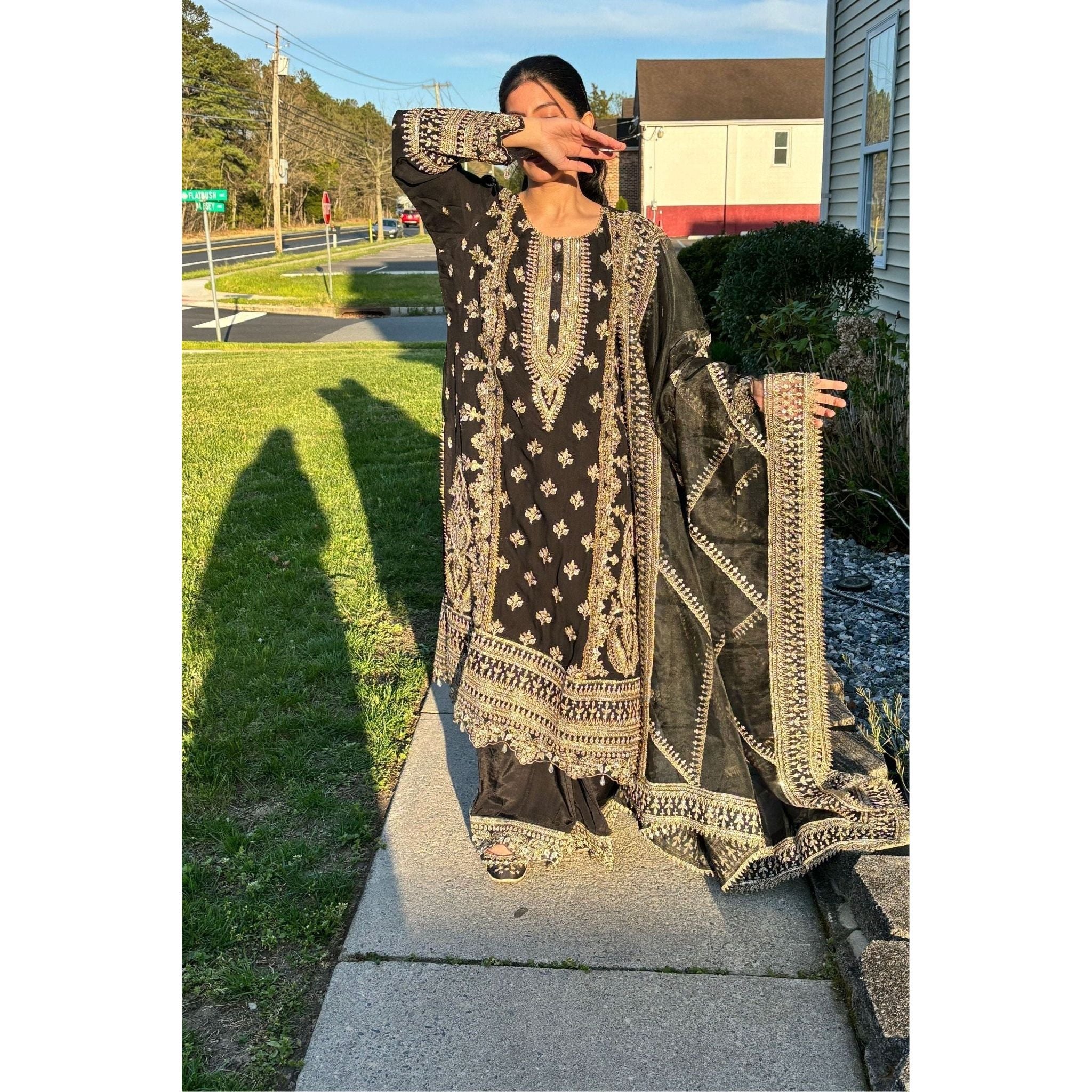 A stunning black suit adorned with beige and gold embroidery, complemented by a dupatta and plazzu pants also embroidered with intricate designs.