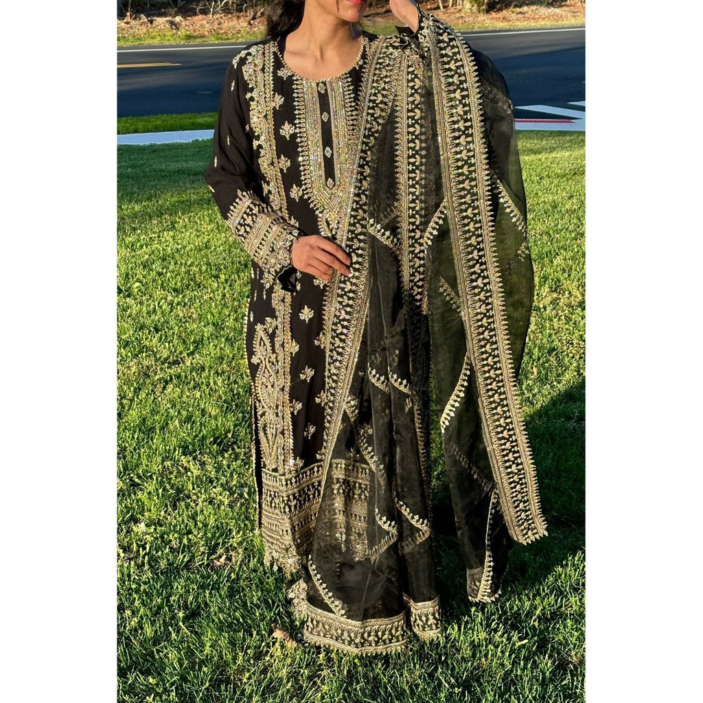 A stunning black suit adorned with beige and gold embroidery, complemented by a dupatta and plazzu pants also embroidered with intricate designs.