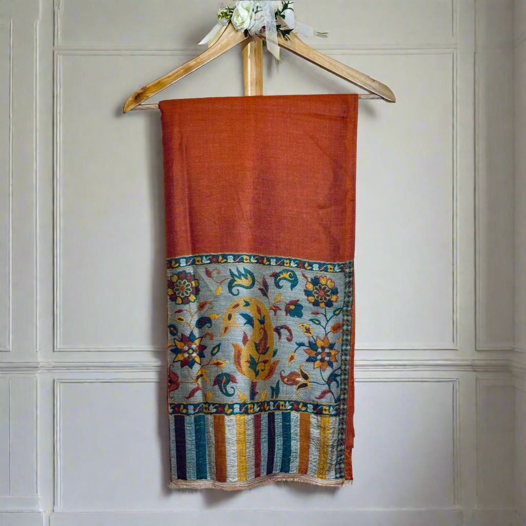 A lightweight, exquisite Shawl woven from Kani yarn in burnt orange hues. The Shawl features a pure silk Pashmina base and a delicate grey border. 