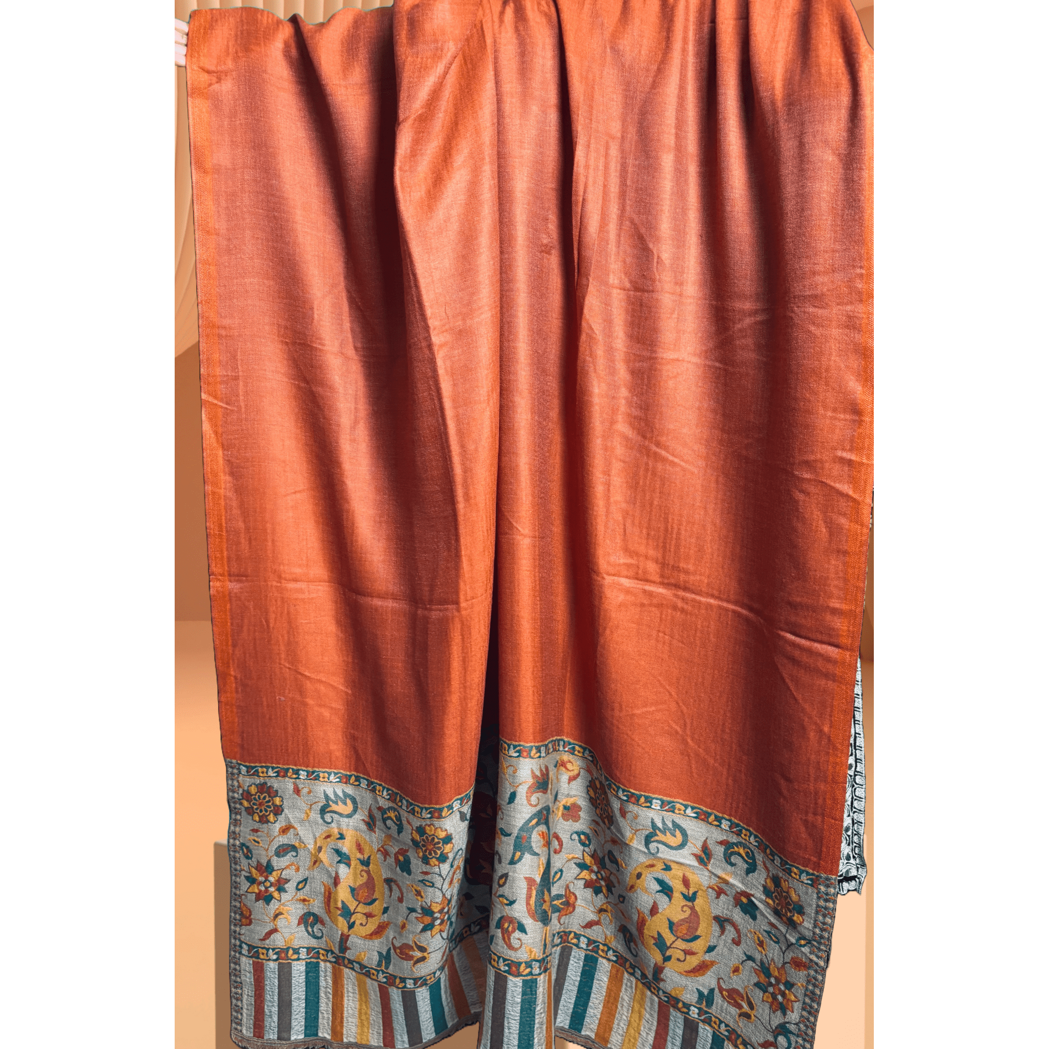 A lightweight, exquisite Shawl woven from Kani yarn in burnt orange hues. The Shawl features a pure silk Pashmina base and a delicate grey border. 