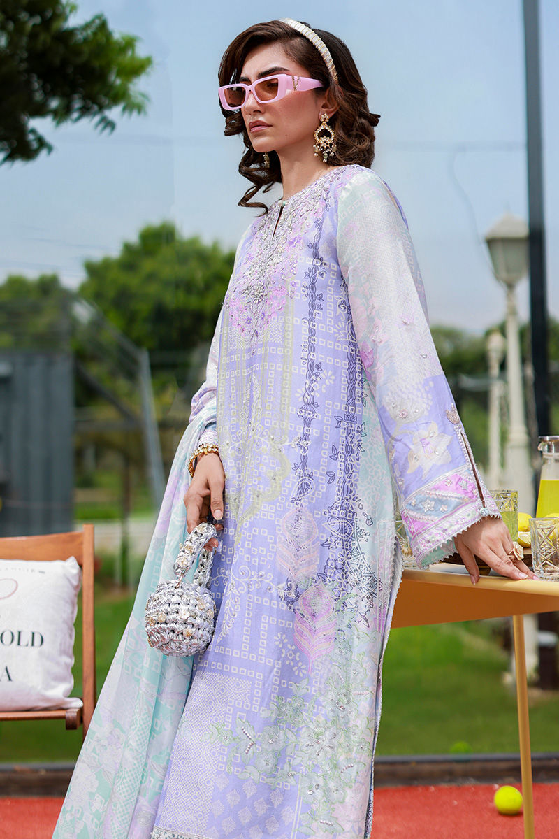 Woman in a pastel-colored outfit with sunglasses and a handbag, standing outdoors.
