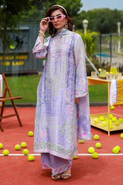 Woman in a light purple and white patterned outfit standing on a tennis court with tennis balls around.