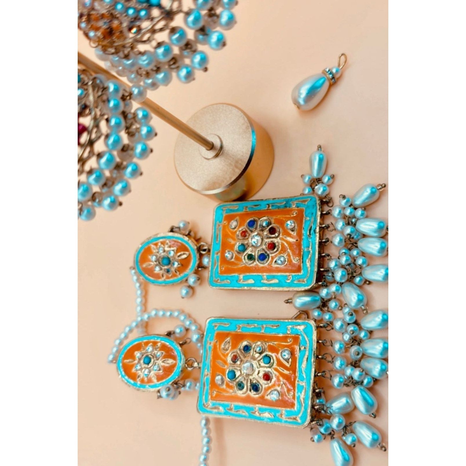 Beautiful handmade earring in light blue and rust color, featuring a pear hanging from it. 